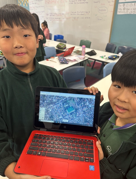 An image of two students presenting their work on a laptop