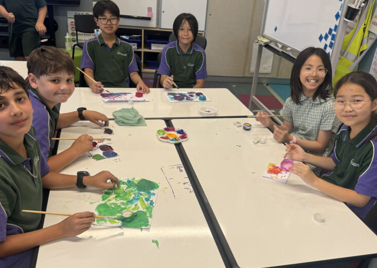 Photo of students around a table in their classroom painting